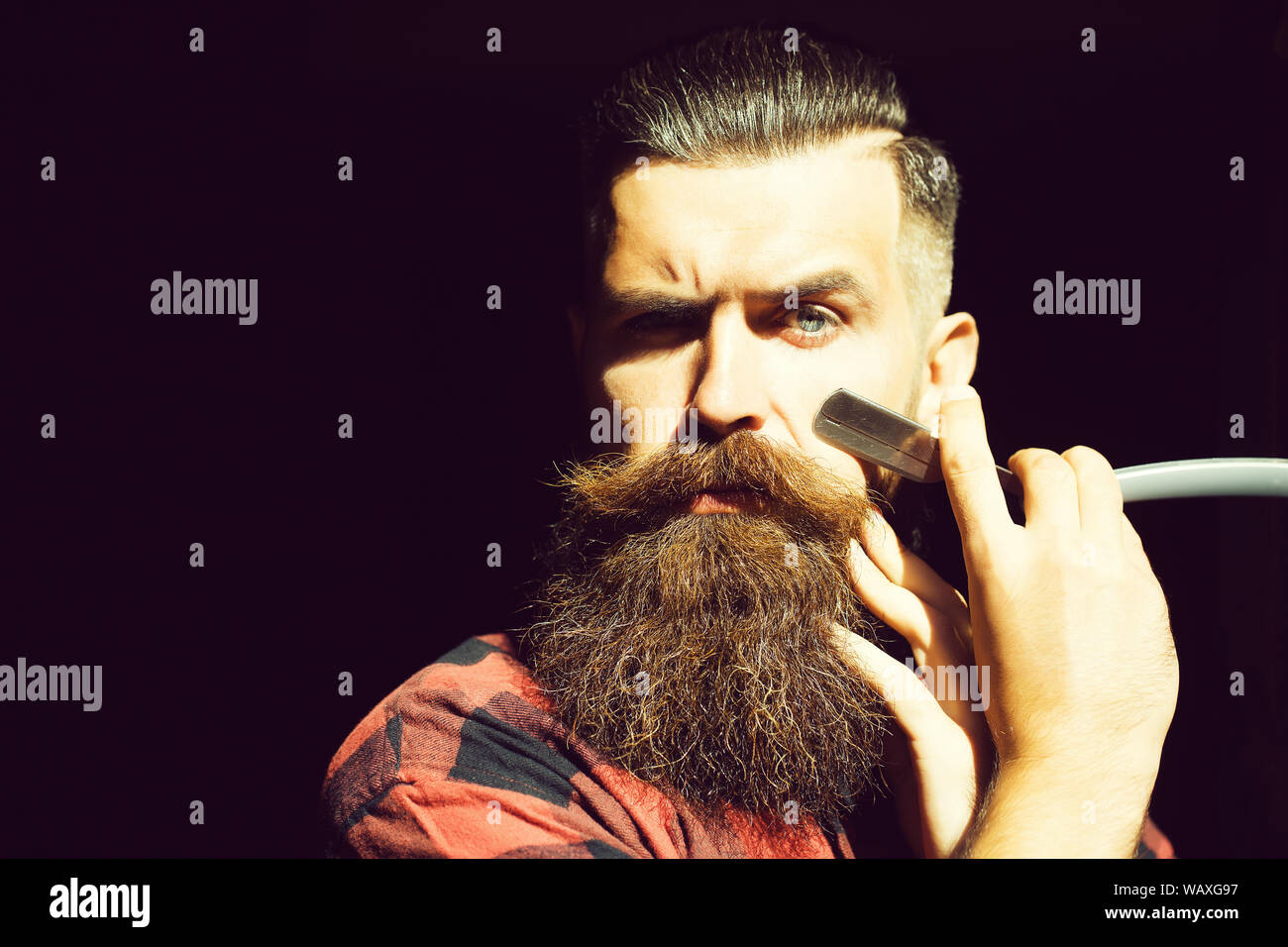 young-man-hipster-with-handsome-bearded-face-holding-cut-throat-razor-near-long-fashion-beard-...jpg